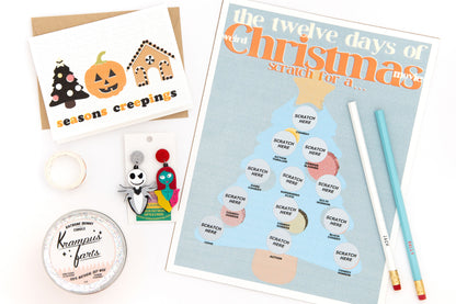 Christmas-themed subscription box with scratch-off movie items art print, pumpkin tree holiday greeting card, Jack and Sally earrings and pencil set, Krampus candle, and decorative washi tape for DIY holiday crafts