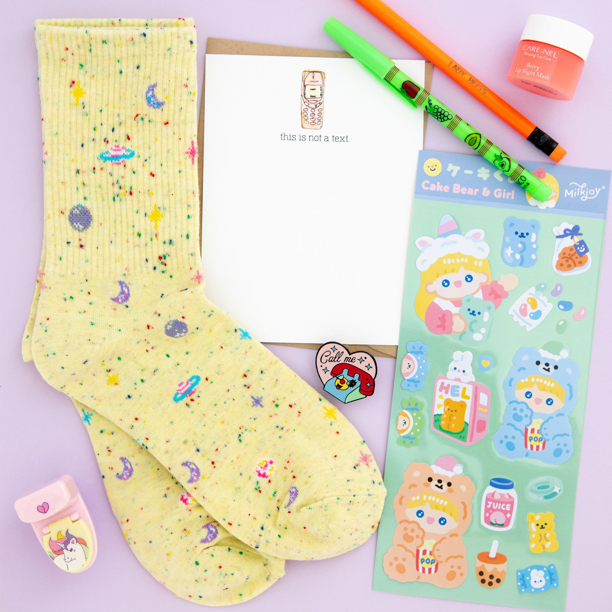 Unleash your inner creativity and imagination with The Oddball Club's unique and quirky subscription box filled with planet-themed socks, a call me enamel nostalgic pin, a cute 'This Is Not a Text' notecard, pop-a-point pencils, adorable cake bear and girl stickers, a kawaii unicorn toilet pencil sharpener, and a fun Ratbone skinny pencil. Order now to experience the perfect blend of fun and functionality!