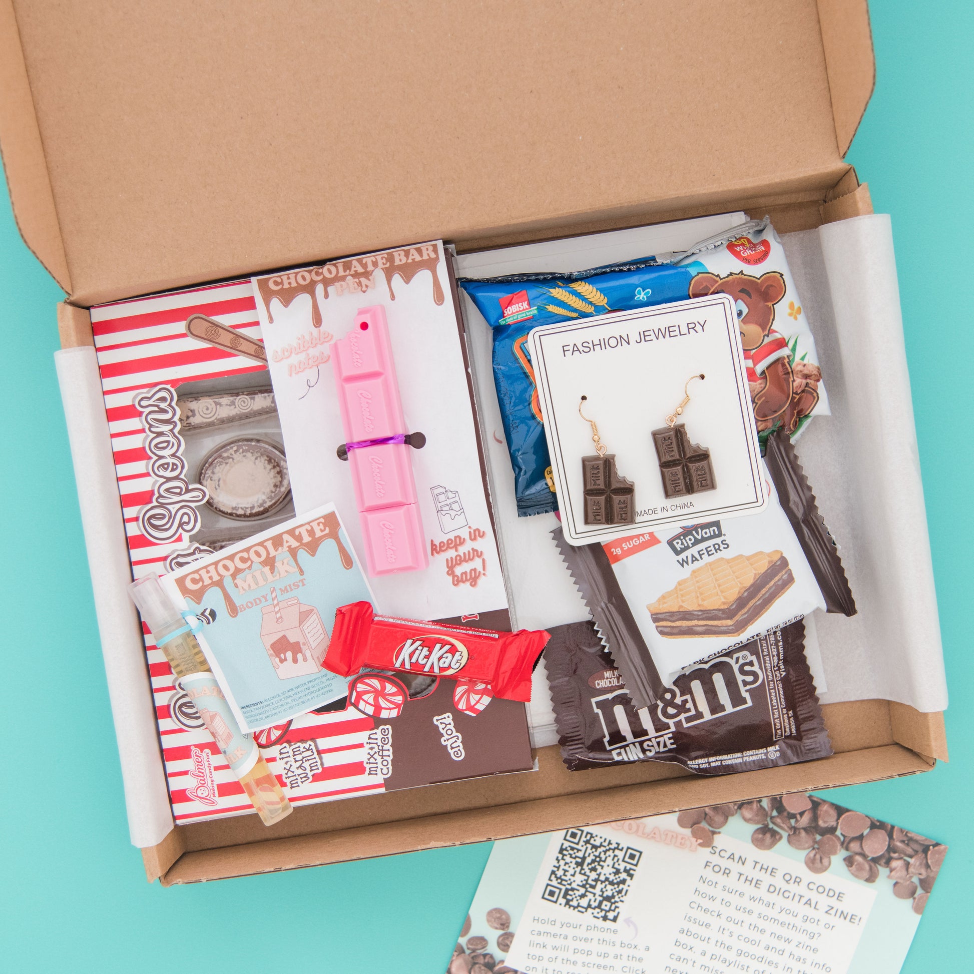 Indulge in a chocolatey delight with our subscription box - featuring a novelty pen, earrings, greeting card, chocolate spoons, and snacks.