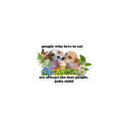 a kiss cut sticker with the julia child quote "people who love to eat are always the best people" with two puppies licking an ice cream cone and sourrounded by flowers, ferns, leaves, and an orange butterfly.